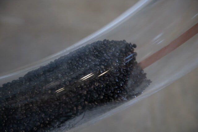 Coffee beans shown moving through a clear pneumatic tube.